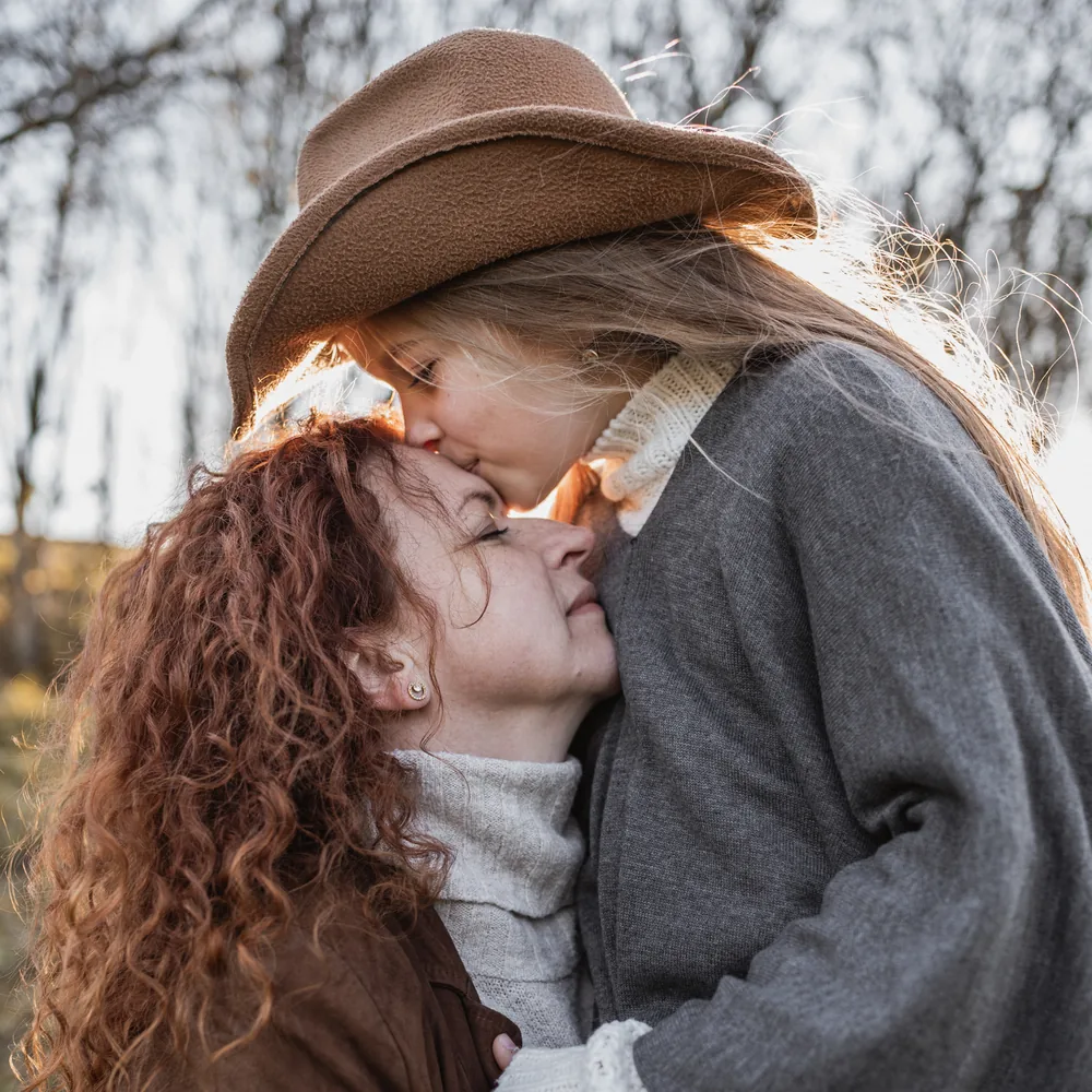 Dcera dává mámě pusu na čelo při rodinném focení, rodinný fotograf